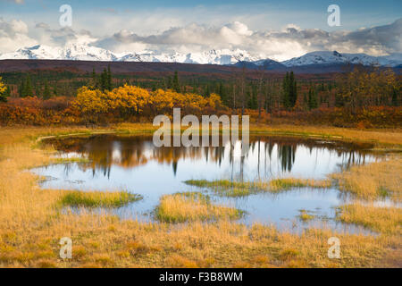 Die Sonne lugt durch eine teilweise bewölkter Himmel, die Alaska Range zu beleuchten Stockfoto