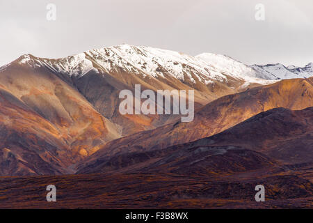 Die Sonne lugt durch eine teilweise bewölkter Himmel, die Alaska Range zu beleuchten Stockfoto