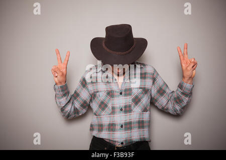 Ein junger Cowboy trägt ein kariertes Hemd posiert vor einer grünen Wand Stockfoto