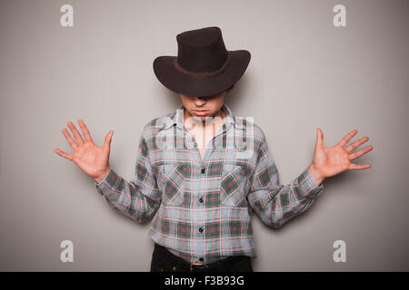Ein junger Cowboy trägt ein kariertes Hemd posiert vor einer grünen Wand Stockfoto