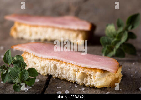 Geröstete Brotscheiben mit geräuchertem Fleisch über rustikale Holz Hintergrund Stockfoto