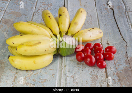 Bananen und kleine Tometo auf dem Holz Hintergrund Stockfoto