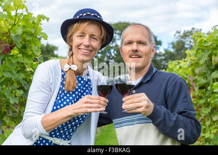 Kaukasische mittleren gealterten paar Toasten mit Gläser Rotwein im Weinberg Stockfoto