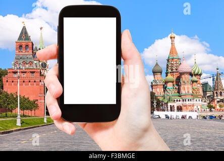 Reisekonzept - Hand hält Smartphone mit Bildschirm und Vasilevsky Abstieg des Roten Platzes mit St Basil Cathedral auf Backg Ausschneiden Stockfoto