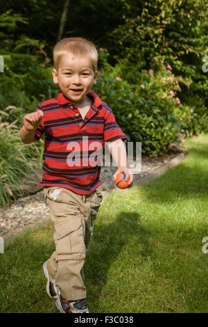 Zwei Jahre alter Junge mit einem kleinen Ball in der Hand in den Hinterhof in Issaquah, Washington, USA Stockfoto