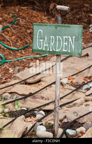 Garten Zeichen und Sackleinen Säcke für Gemüsegarten, Mulch, Schutz vor Unkraut und winterfest zu machen, zeigt Tropfenfänger Bewässerung Rohre Stockfoto