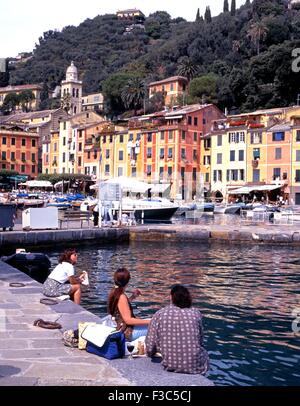 Touristen sitzen auf der Hafenseite mit Mittagessen mit Blick auf die Ansicht, Portofino, Ligurien, Italien, Westeuropa. Stockfoto