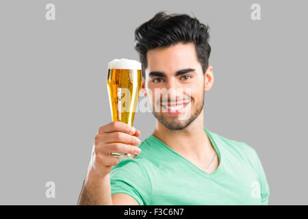 Porträt von gut aussehenden jungen Mann Verkostung ein Bier vom Fass, auf grauem Hintergrund isoliert Stockfoto