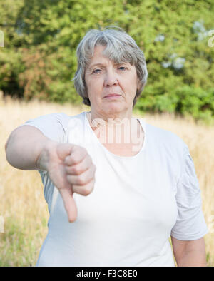 Alter Frau zeigt Daumen nach unten Stockfoto