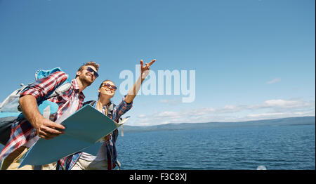 Fröhliche Wanderer mit Karte tatenlos am Meer Stockfoto