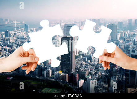 Hände mit grünen Puzzle über Stadt Hintergrund Stockfoto