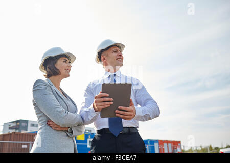 glückliche Bauherren in Schutzhelme mit Tablet-pc im freien Stockfoto