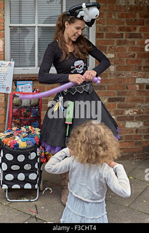 Weibliche Straße Entertainer einen Ballon für eine animierte Kind zu gestalten. England-UK Stockfoto