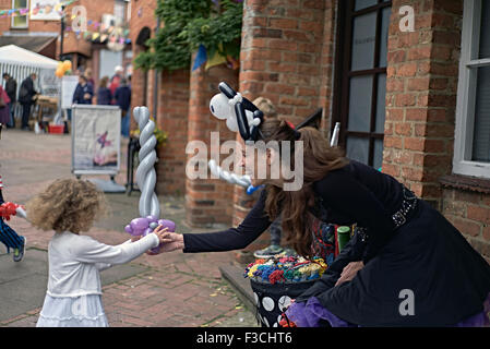 Weibliche Straße Entertainer präsentiert ein Kind mit geformten Ballon. England-UK. Stockfoto