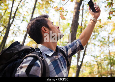 Porträt eines Mannes Suche Verbindung auf dem Telefon im Wald Stockfoto