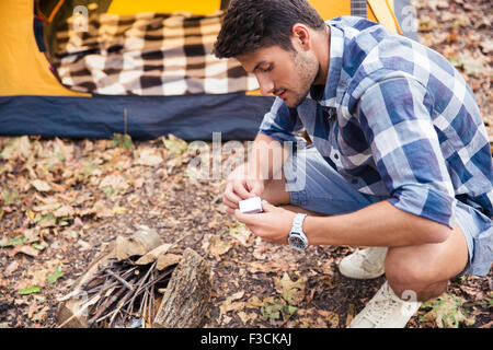 Porträt eines jungen Mannes Kindle Lagerfeuers im Wald Stockfoto