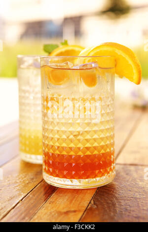 Eistee und Limonade mit Scheiben von Orange und Zitrone außerhalb auf einem Holztisch Stockfoto