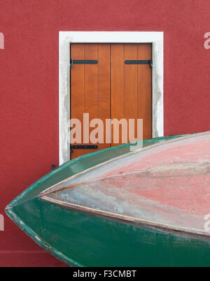 Eine grüne Boot gegen ein Fenster mit geschlossenen Fensterläden Stockfoto