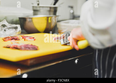 Koch Schneiden von Fleisch auf Schneidebrett Stockfoto