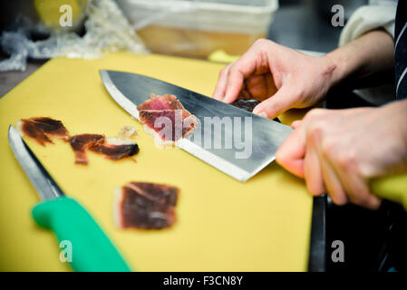 Koch schneiden dünne Scheiben von Fleisch Stockfoto