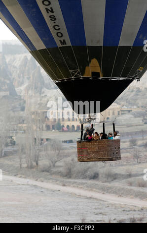 Heißluftballon im Flug voller Touristen in Kappadokien, Puten mit schroffen Felsen und Ruinen Hintergrund Stockfoto