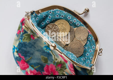 Lockerer Wechsel in hübscher blumiger Handtasche auf weißem Hintergrund - Cost of Living Concept UK Stockfoto