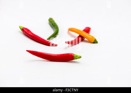Fünf grüne, gelbe und rote Chilis (Capsicum annuum), auf einem weißen Tabelle angezeigt Stockfoto