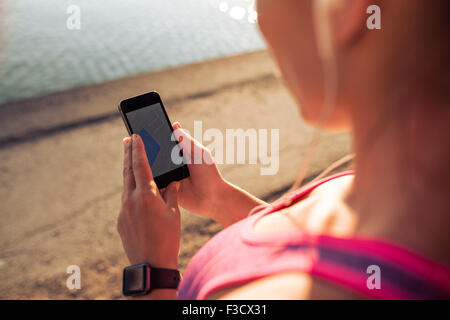 Nahaufnahme Bild von Frau liest eine SMS-Nachricht auf ihr Handy. Sportliche Frau mit Smartphone während der Einnahme einer Pause von outd Stockfoto