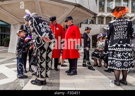 Pearly King schüttelt Hände mit einem perlweißen Prinzen bei der Pearly Kings und Queens Erntedankfest, die Guildhall, London, UK Stockfoto