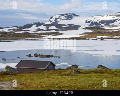 Panorama-Ansicht im norwegischen Bergen, kleine Hütte, See, Flecken von Schnee und entfernten Gletscher, Finse, Hardangervidda-Norwegen Stockfoto