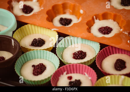 Reihen von bunten Tassen. Muffins-Vorbereitung zu Hause. Stockfoto