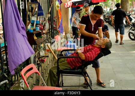 Ein Mann hat eine Rasur bei Streetside Barbier in Ho-Chi-Minh-Stadt, Vietnam Stockfoto