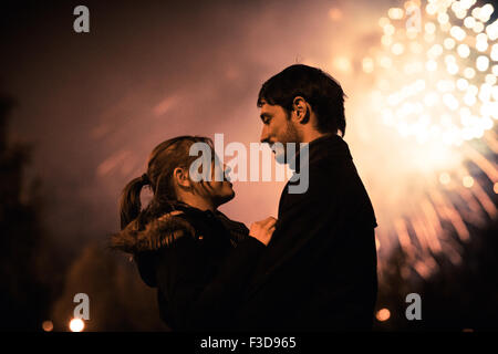 Eine Silhouette eines küssenden Paares vor einem riesigen Feuerwerk. Gefilterten Bild mit Korn Stockfoto