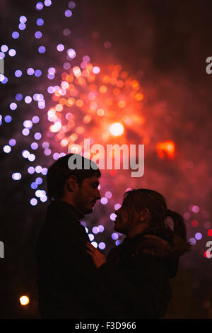 Eine Silhouette eines küssenden Paares vor einem riesigen Feuerwerk. Gefilterten Bild mit Korn Stockfoto