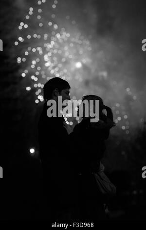 Eine Silhouette eines küssenden Paares vor einem riesigen Feuerwerk. Gefilterte schwarz / weiß Bild mit Korn Stockfoto