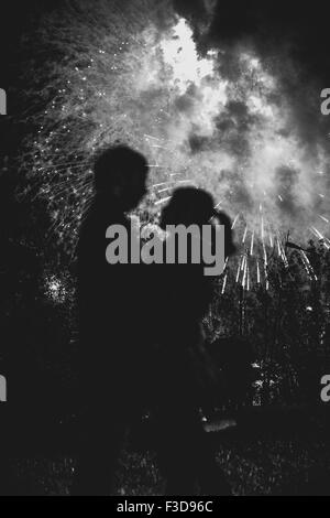 Eine Silhouette eines küssenden Paares vor einem riesigen Feuerwerk. Gefilterte schwarz / weiß Bild mit Korn Stockfoto
