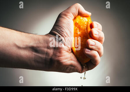 dramatische Mann drückt Orange. Konzept drückte einen Mann ist müde von der Arbeit. Stockfoto