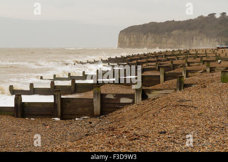 Stürmische steiniger Strand, Wellen, die mit Buhnen leisten. Winchelsea Strand, Winchelsea Strand, Hastings, Kent, England, Vereinigtes König Stockfoto