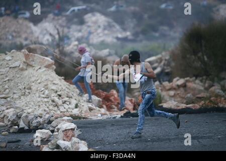 (151005)--RAMALLAH, 5. Oktober 2015 (Xinhua)--A palästinensische Demonstranten schleudert Steinen auf israelische Soldaten bei Zusammenstößen in der Nähe der jüdischen Siedlung Beit Eil, in der Nähe von der Westbank Ramallah am 5. Oktober 2015. (Xinhua/Fadi Aruri) Stockfoto