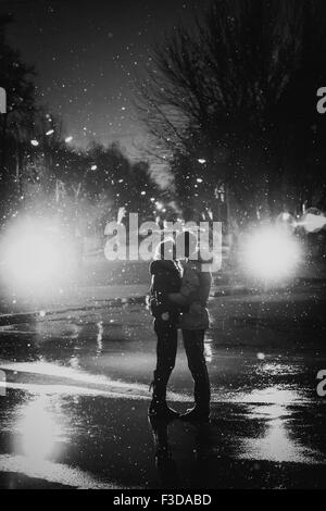 In Liebe Paar küssen im Schnee bei Nacht Stadt Straße schwarz / weiß Stockfoto