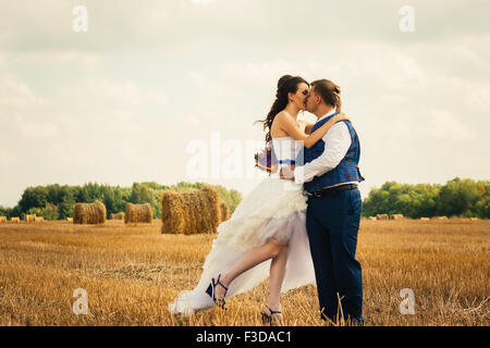 Braut und Bräutigam in der Nähe von Heu auf einem ländlichen Gebiet Stockfoto