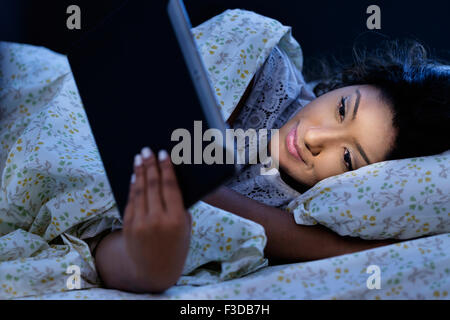 Junge Frau mit Tablet im Bett Stockfoto