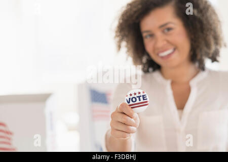 Junge Frau Holding stimmberechtigten Abzeichen und lächelnd Stockfoto