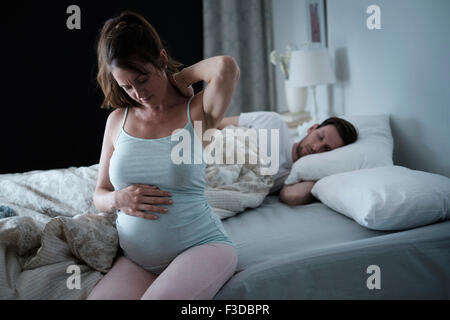 Frau sitzt auf dem Bett und steifen Nacken dehnen Stockfoto