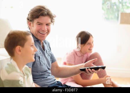 Kinder (8-9, 10-11) vor dem Fernseher mit ihrem Vater Stockfoto