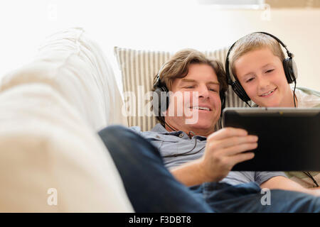 Mann mit Tablet-pc mit seinem Sohn (8-9) auf sofa Stockfoto