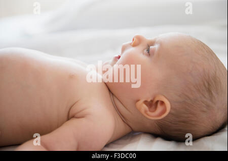 Babymädchen (2-5 Monate) auf Bett liegend Stockfoto