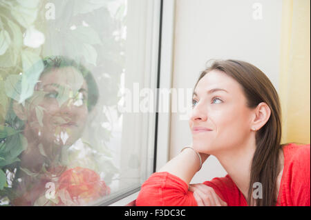 Lächelnde Frau Blick durch Fenster Stockfoto