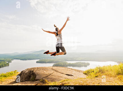Junge Frau, die einen Sprung über Berggipfel, Rückansicht Stockfoto