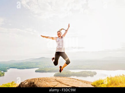 Junge Frau über Berggipfel springen Stockfoto